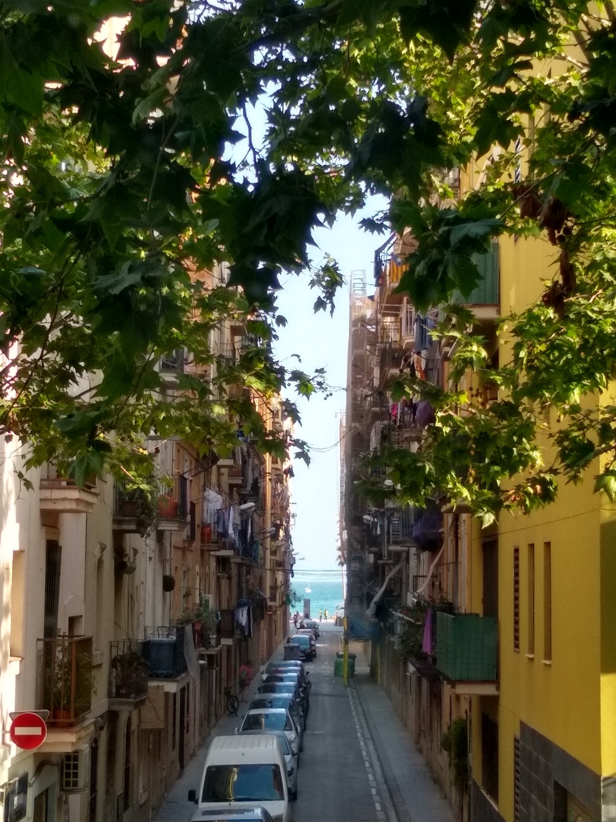 A street in Barcelona ending with a beach at the end